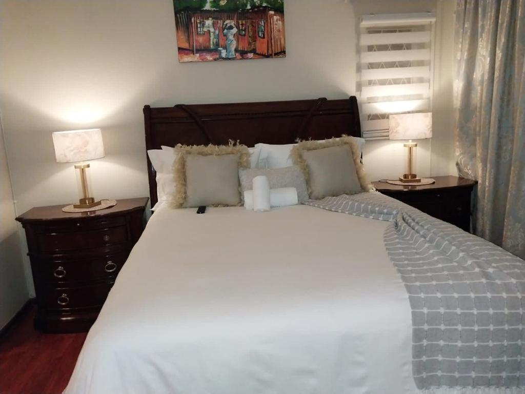 a bedroom with a large white bed with two lamps at Liyoli Guesthouse in Mthatha