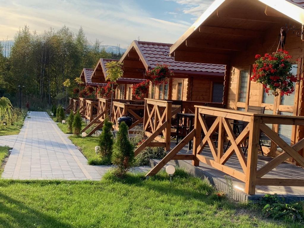 una casa de madera con una valla en el patio en ZIELONA DOLINA - kompleks dla rodzin z dziećmi en Mikołajki