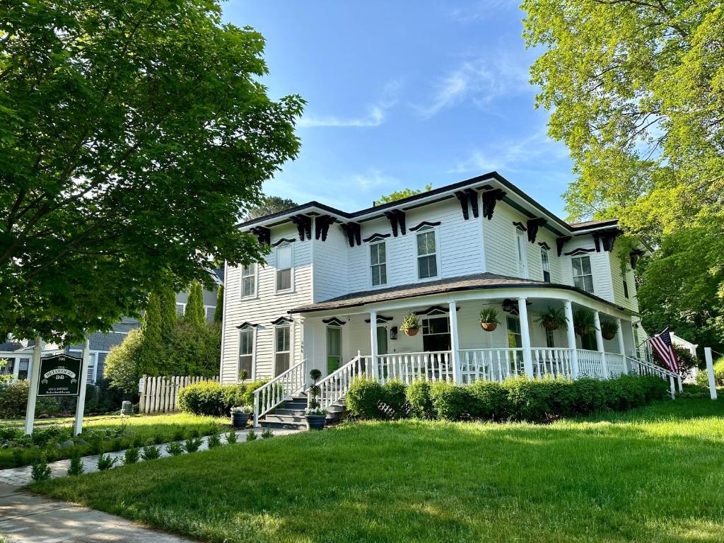 uma grande casa branca com um alpendre em The Belvedere B&B em Charlevoix