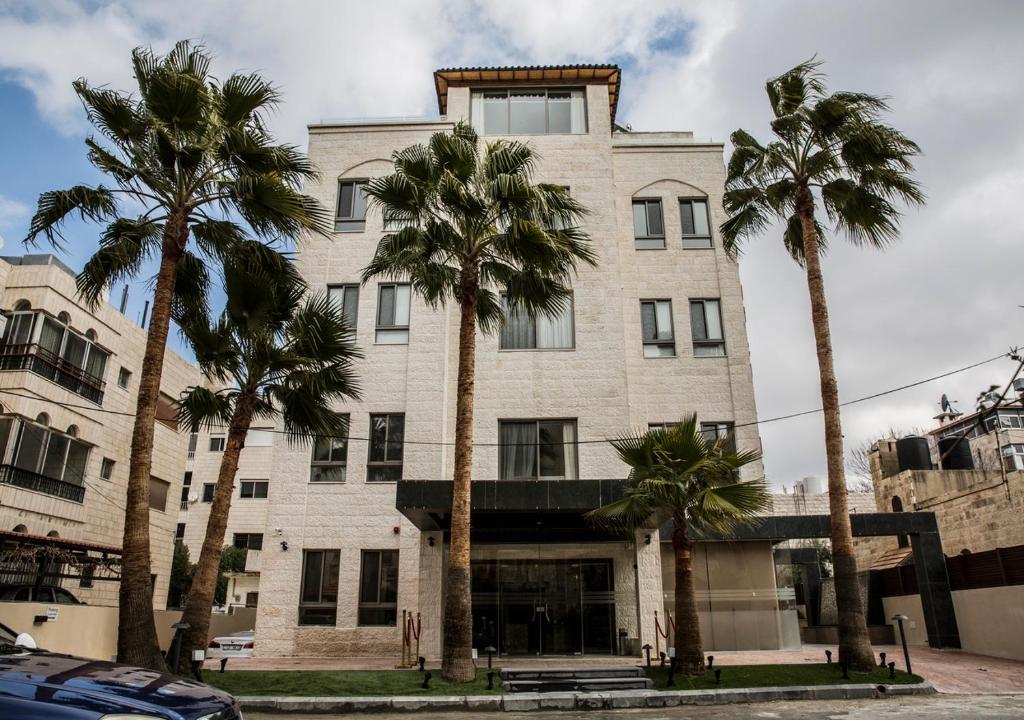 a building with palm trees in front of it at Naylover Hotel Suites in Amman