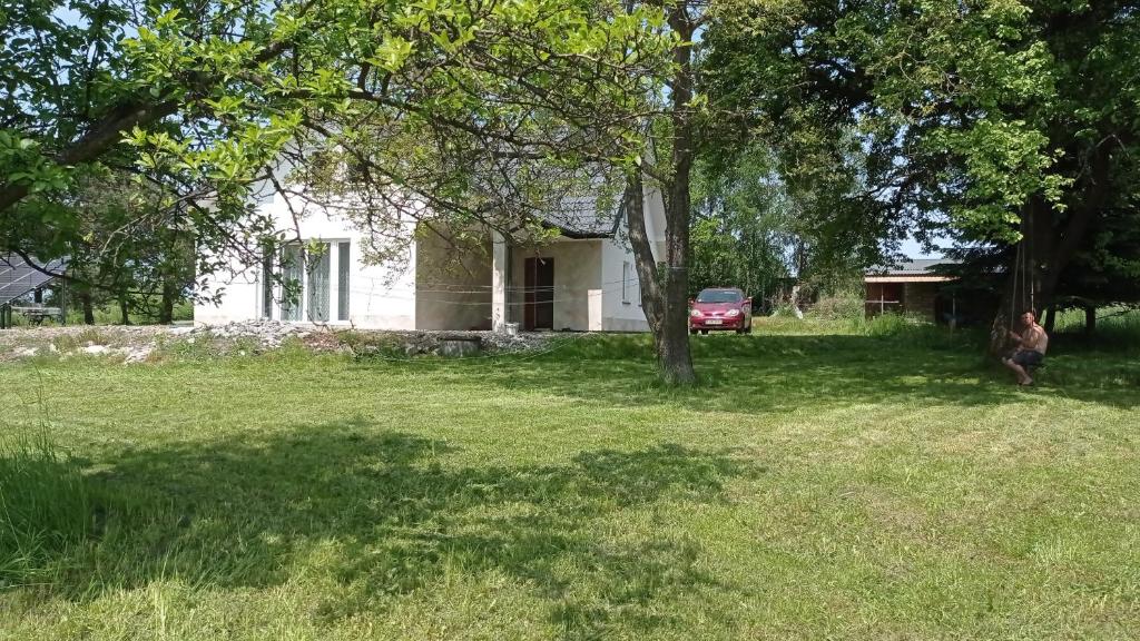 a person sitting in the grass in front of a house at Oaza Miłości in Lipniki