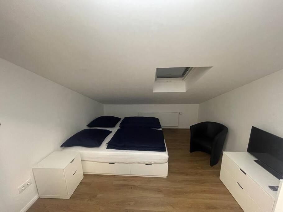 um quarto com uma cama branca e uma cadeira preta em Buxtehude*Wohnung*100qm*6 Schlafplätze*NEU* em Buxtehude