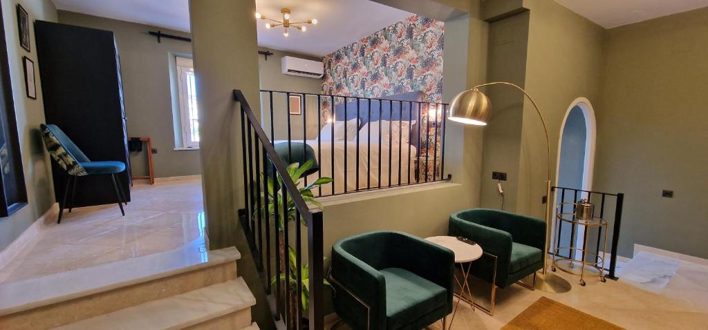 - un salon avec des chaises vertes et un escalier dans l'établissement Boutique Suites, à Arcos de la Frontera