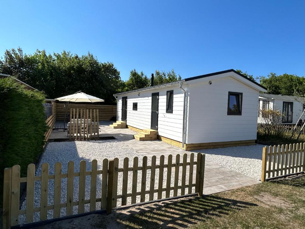 a backyard with a fence and a white shed at Breezy Beach Chalet in Petten