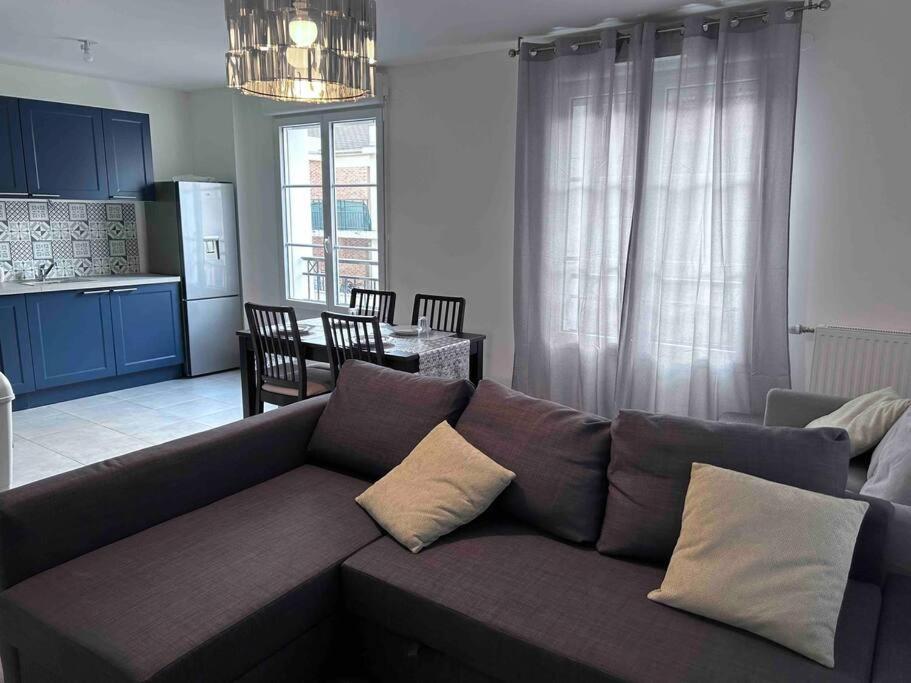een woonkamer met een bank en een keuken bij Bel appartement en centre-ville in Le Blanc-Mesnil