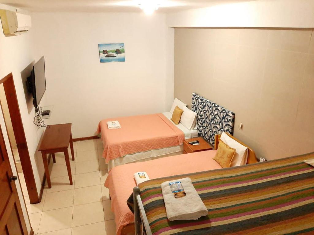 イキトスにある102 RV APARTMENTS IQUITOS-APARTAMENTO FAMILIAR CON PISCINAのベッド2台とテレビが備わるホテルルームです。