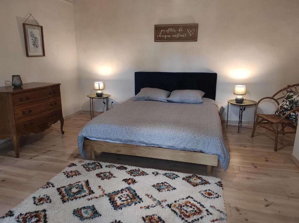 a bedroom with a bed with two lamps and a rug at Gîte à la campagne, proche Carcassonne in Alairac