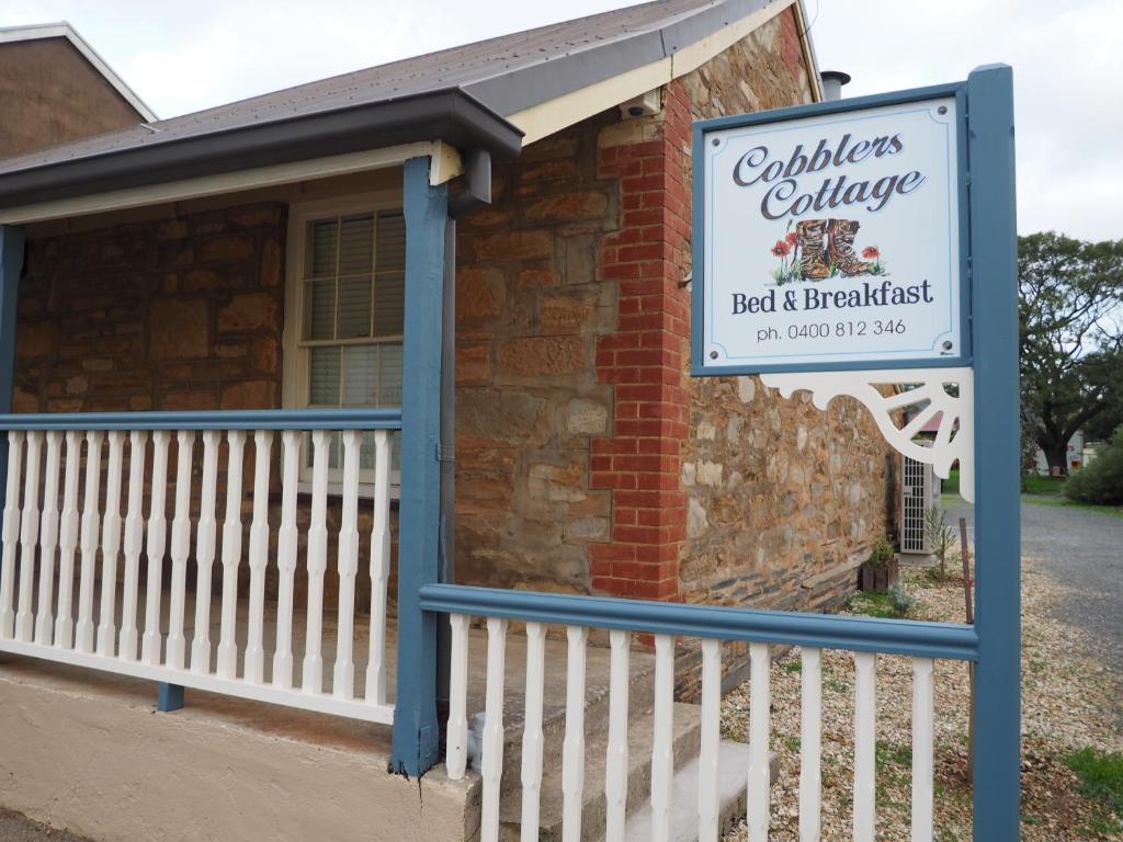 a sign in front of a building with a house at Cobblers Cottage B&B in Willunga