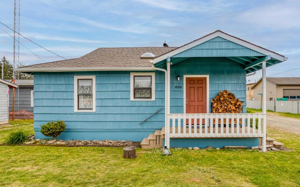 パシフィック・シティにあるSea Breeze Cottageの白いポーチのある青い家