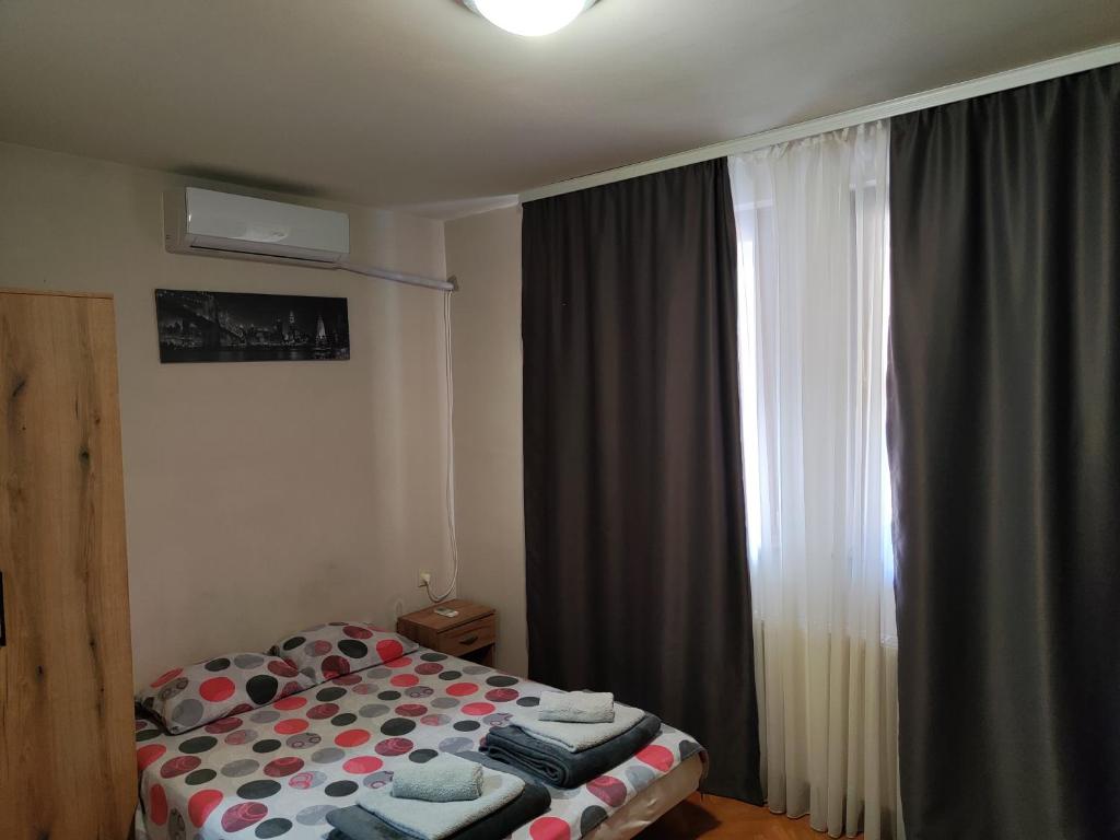um pequeno quarto com uma cama e uma janela em Marger apartment em Niš