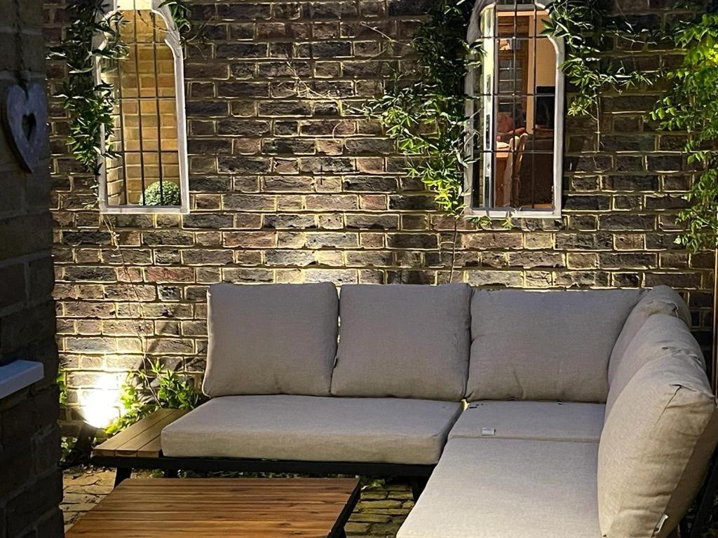 un sofá frente a una pared de ladrillo con 2 ventanas en Serendipity, en Broadstairs