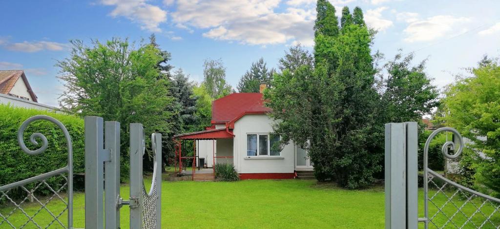una pequeña casa con techo rojo y valla en Play and Relax in Lake-Parkside Cozy Family Retreat - Jegenye Cottage en Zamárdi