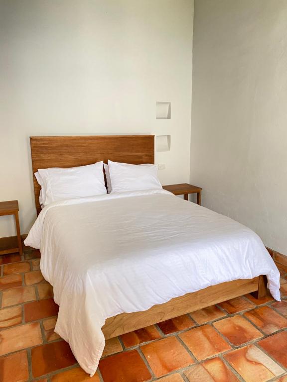 um quarto com uma grande cama branca e uma cabeceira em madeira em Casa Santo Domingo Guadalupe Santander em Guadalupe