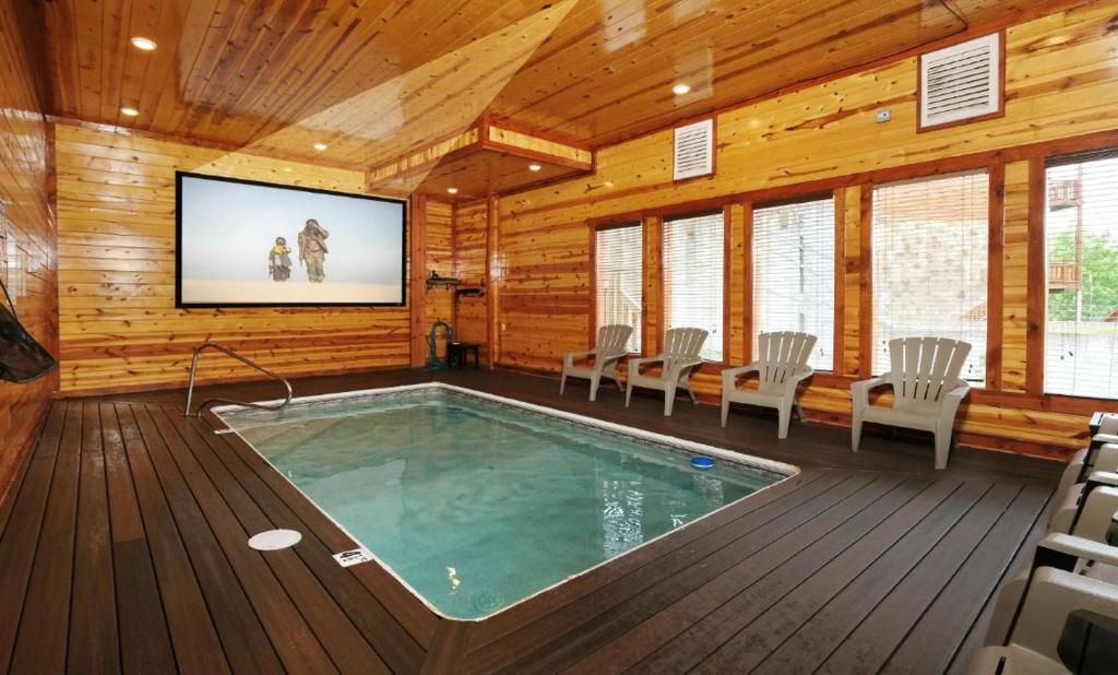 une chambre avec une piscine et une télévision dans une maison en bois dans l'établissement Splash Mountain Lodge, à Pigeon Forge