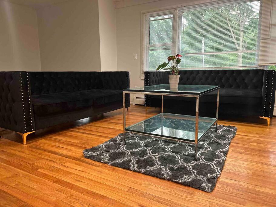 a living room with a black couch and a glass table at Charming 6BR 2 Ba Secluded Retreat walk to the shore in Long Branch