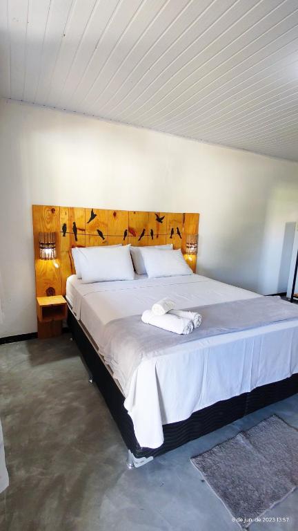 a bedroom with a large bed with a wooden headboard at Pousada Siriba in Caravellas