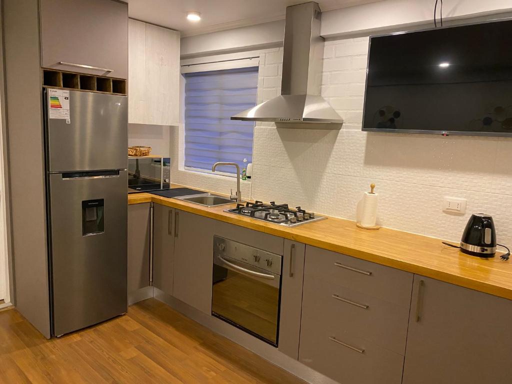 La cuisine est équipée d'un réfrigérateur en acier inoxydable et d'un évier. dans l'établissement Lindo Apartamento, full equipado -Factura empresas-, à Quillota