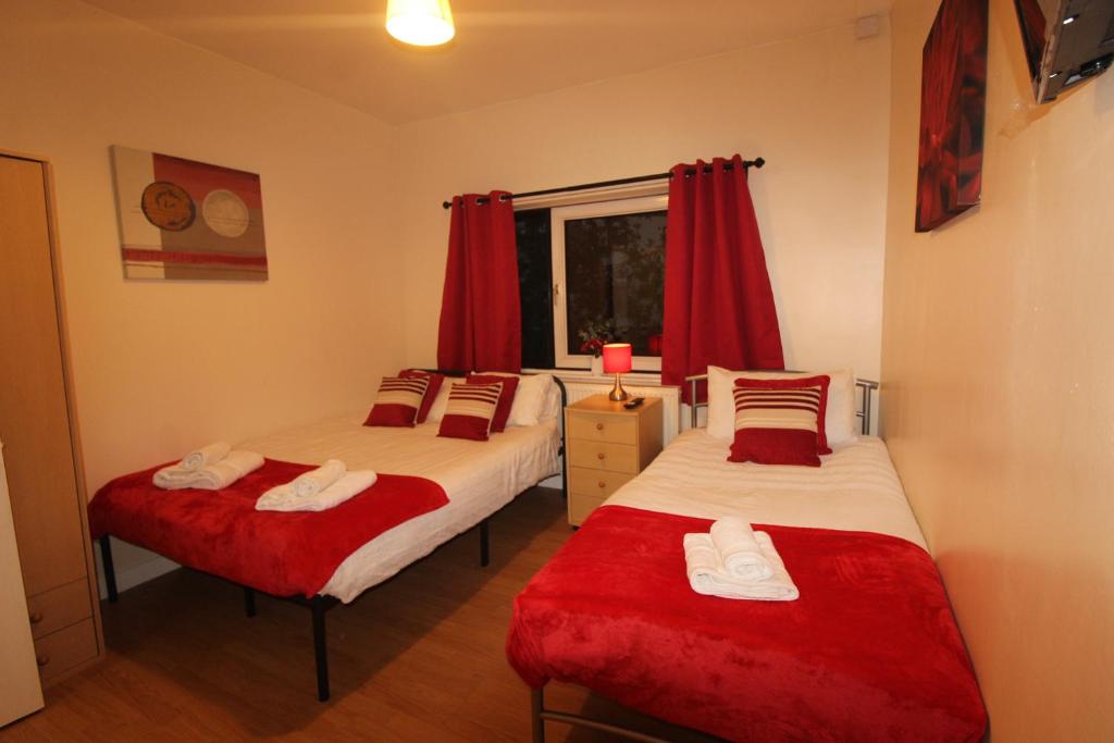Staveley的住宿－Middlecroft House，配有红色窗帘的客房内的两张床