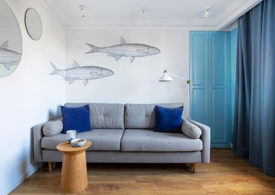 a living room with a couch and fishes on the wall at Blue Apartment Gdańsk in Gdańsk