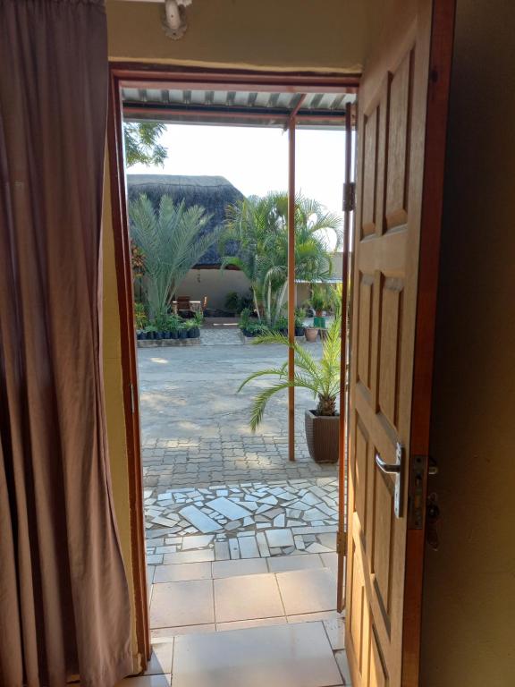 an open door leading to a patio with palm trees at camila guest house in Rundu