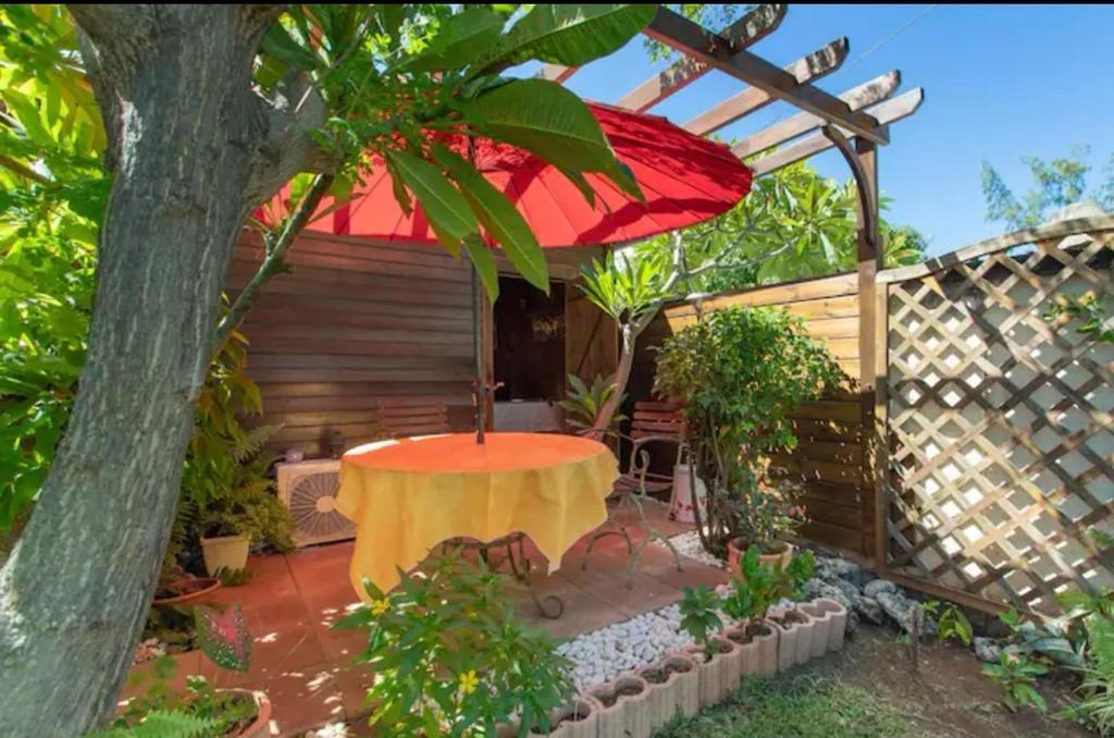 聖魯的住宿－Leu lagon，一个带桌子和红色遮阳伞的庭院
