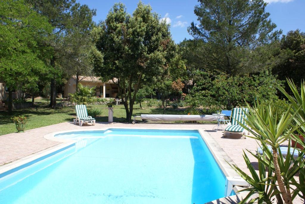una piscina con 2 sillas de césped y árboles en Manor Norbert, en Ventenac-Cabardès