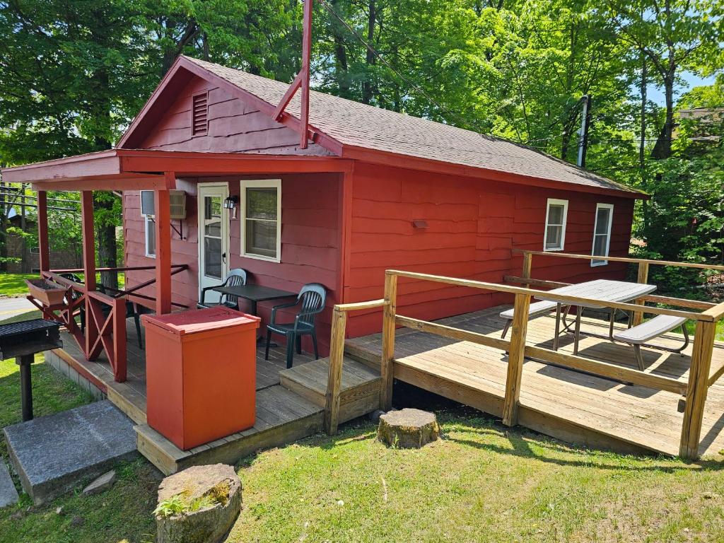 a red cabin with a deck and a table at The Gold Eagle in Lake George