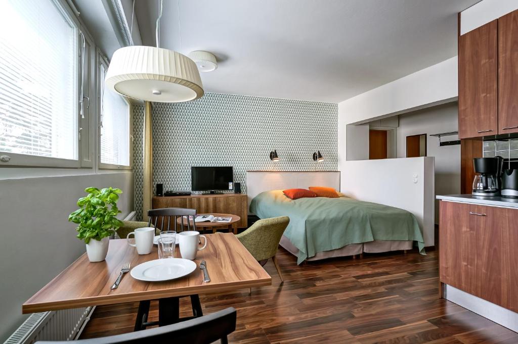 a bedroom with a bed and a table and a kitchen at Forenom Serviced Apartments Espoo Tapiola in Espoo