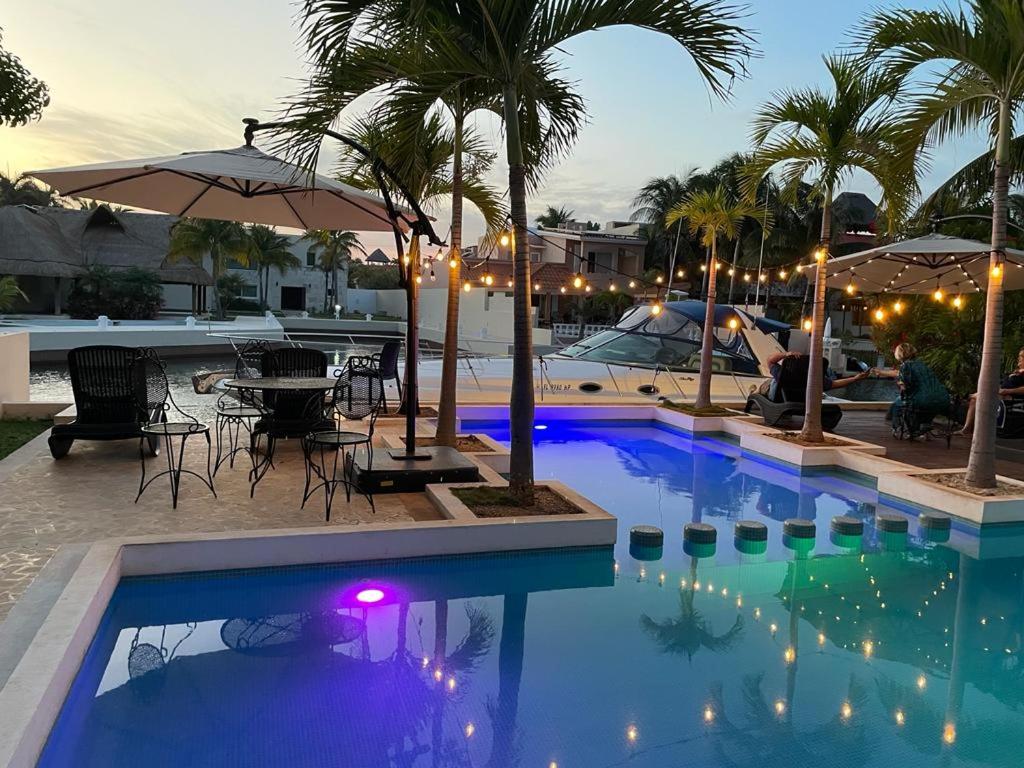 a swimming pool with a table and palm trees and lights at Hermosa mansión en Puerto Aventuras con alberca in Puerto Aventuras