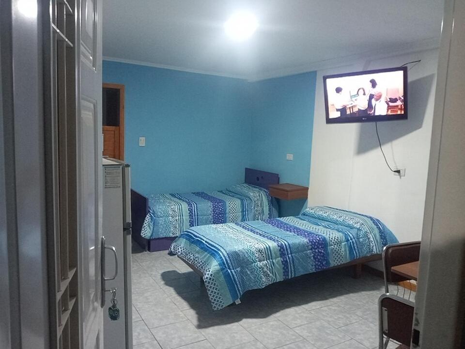 a room with two beds and a tv on the wall at 365 Dptos in Villa Regina