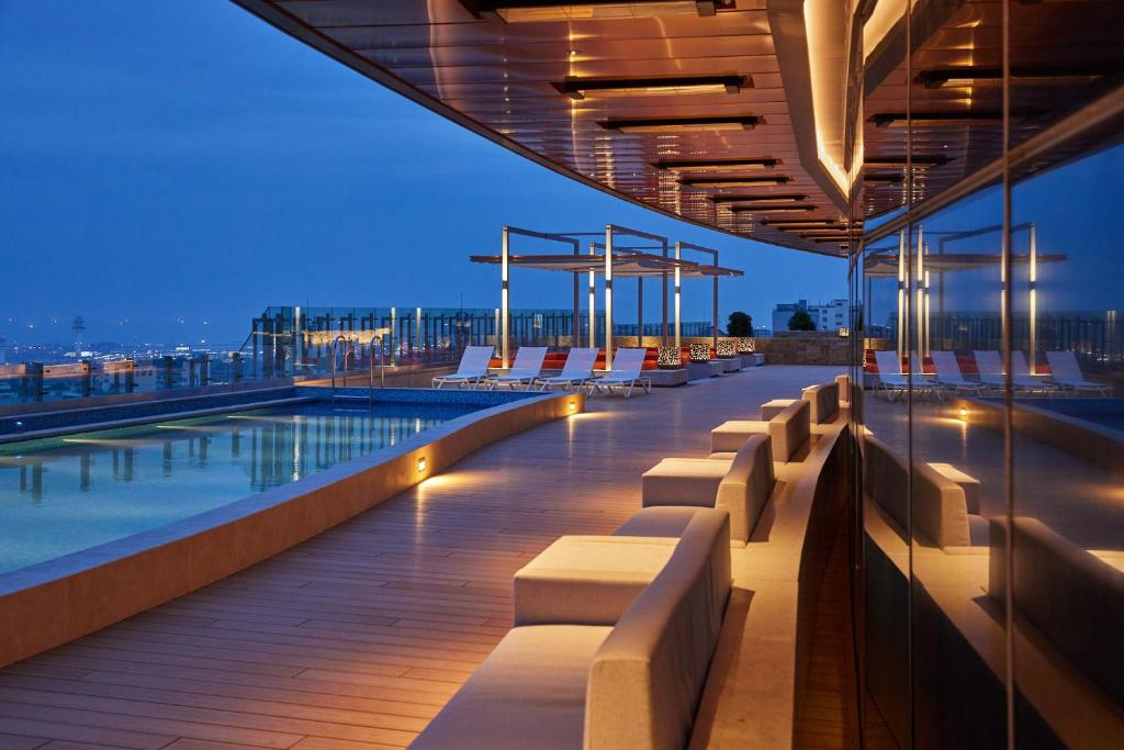 a rooftop deck with chairs and a pool at night at LOTTE City Hotel Jeju in Jeju