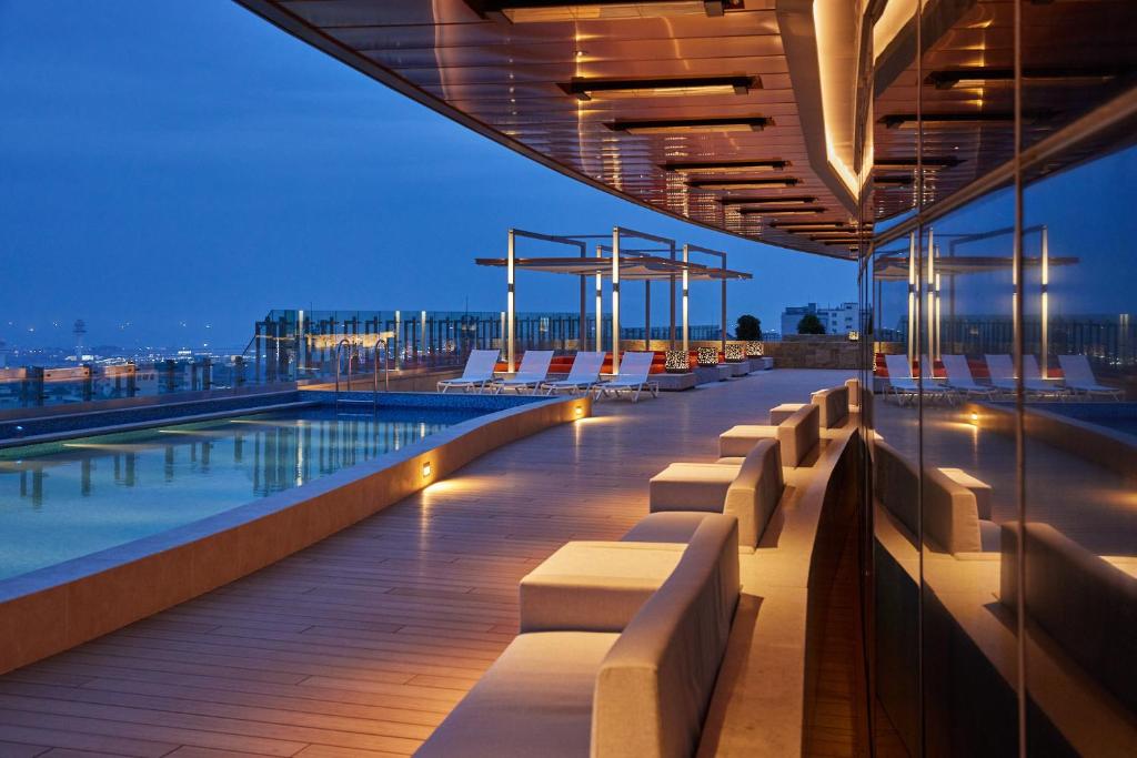a rooftop deck with chairs and a pool at night at Lotte City Hotel Jeju Airport in Jeju