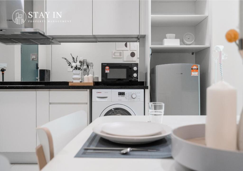 a white kitchen with a table with a plate on it at Atria Sofo Suites - Petaling Jaya in Petaling Jaya