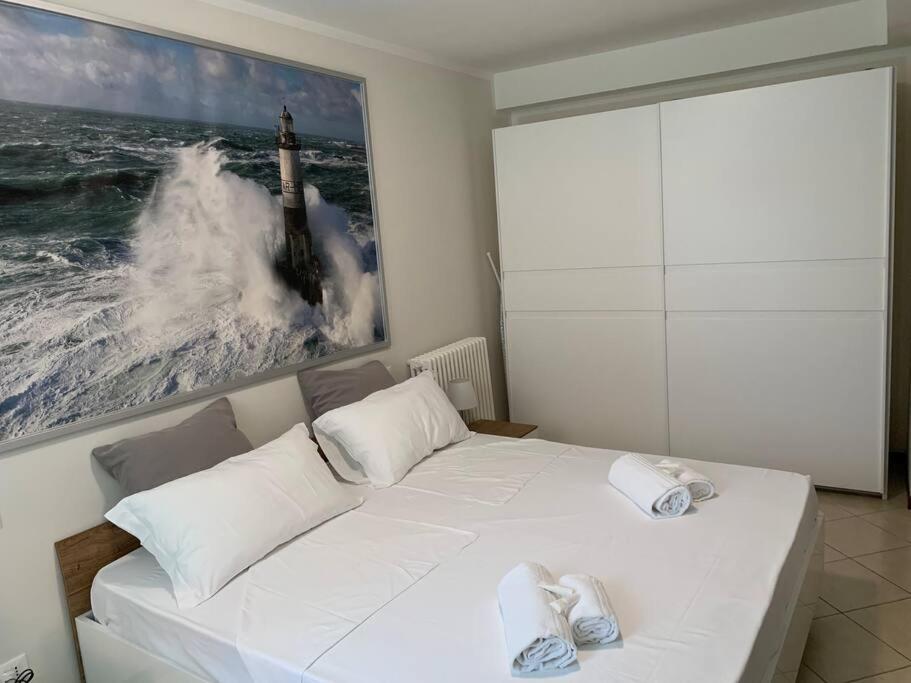Un dormitorio con una cama blanca con una foto de un faro en Casa Magenta Apartment 1, en Valeggio sul Mincio