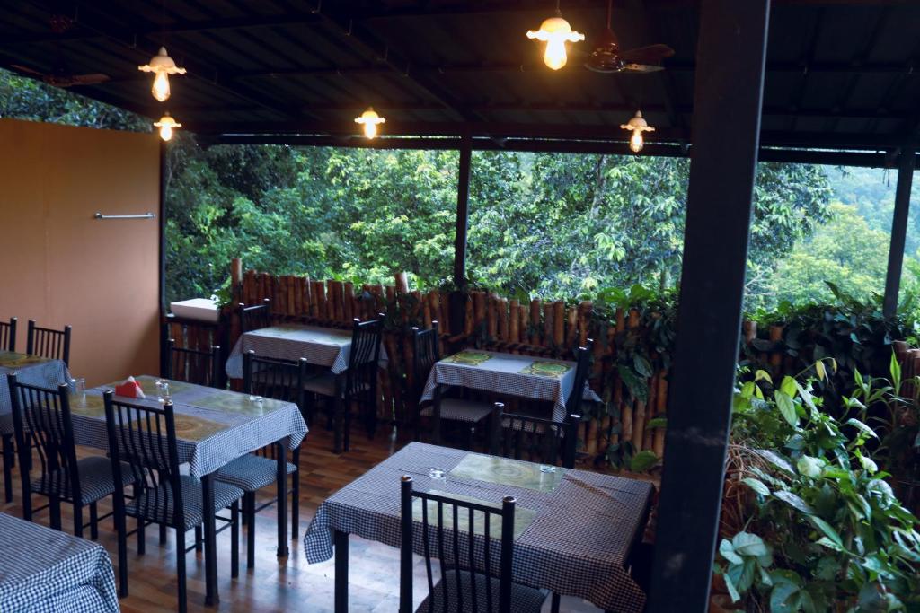 a restaurant with tables and chairs and a large window at Edens Munnar in Munnar