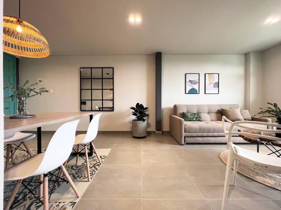 uma sala de estar com um sofá, uma mesa e cadeiras em Parallelo loft Salento P5 em Salento