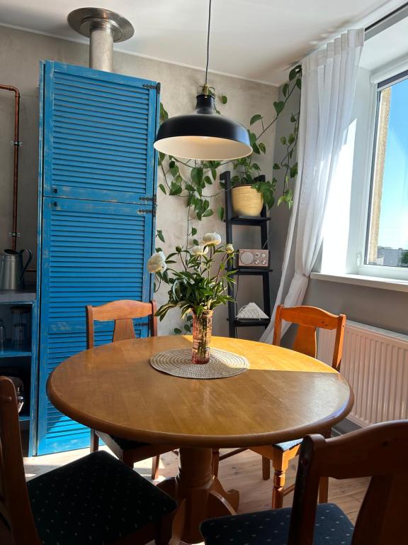 een eettafel met een vaas met bloemen erop bij Mareena_apartments in Liepāja