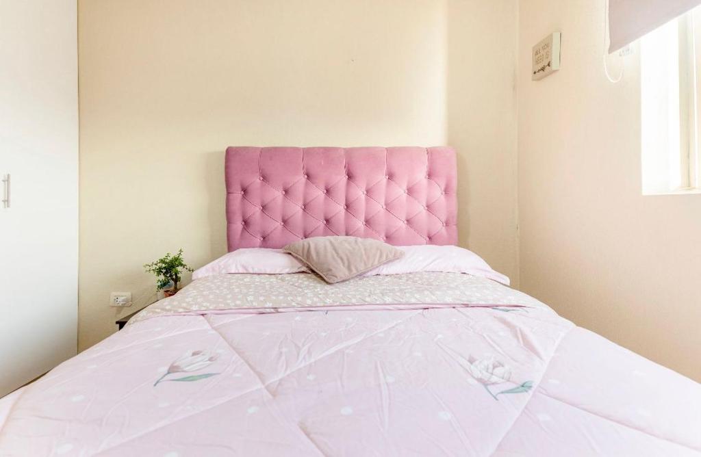 a pink bed with a pink headboard in a bedroom at Linda Habitación Individual con Baño compartido, TV e Internet de Alta Velocidad Cerca al Aeropuerto y a la Arena 1 in Lima