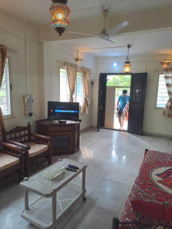 a living room with a person walking out the door at Whispering Winds in Pune