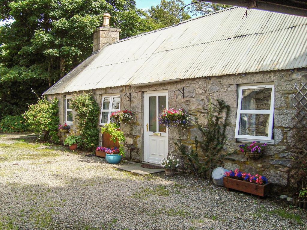 a stone cottage with flowers in front of it at The Bothy At Willowbank in Grantown on Spey