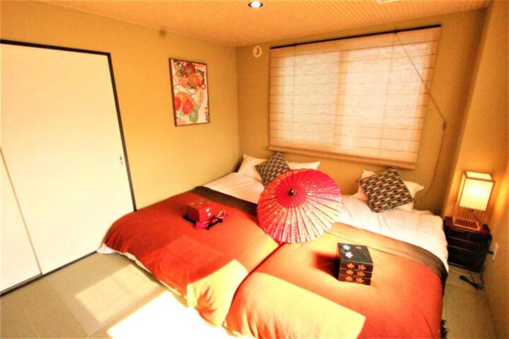 a bedroom with two beds and a red umbrella at Wayado Sapporo Ciao in Sapporo