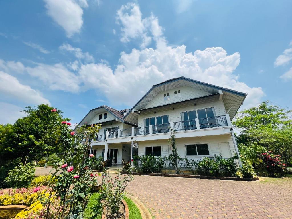 une grande maison blanche avec une allée en briques dans l'établissement PJ Guest House, à Chiang Rai