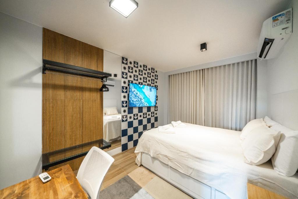 1 dormitorio con 1 cama blanca, mesa y silla en Studio247 Experience by Haven en Brasilia