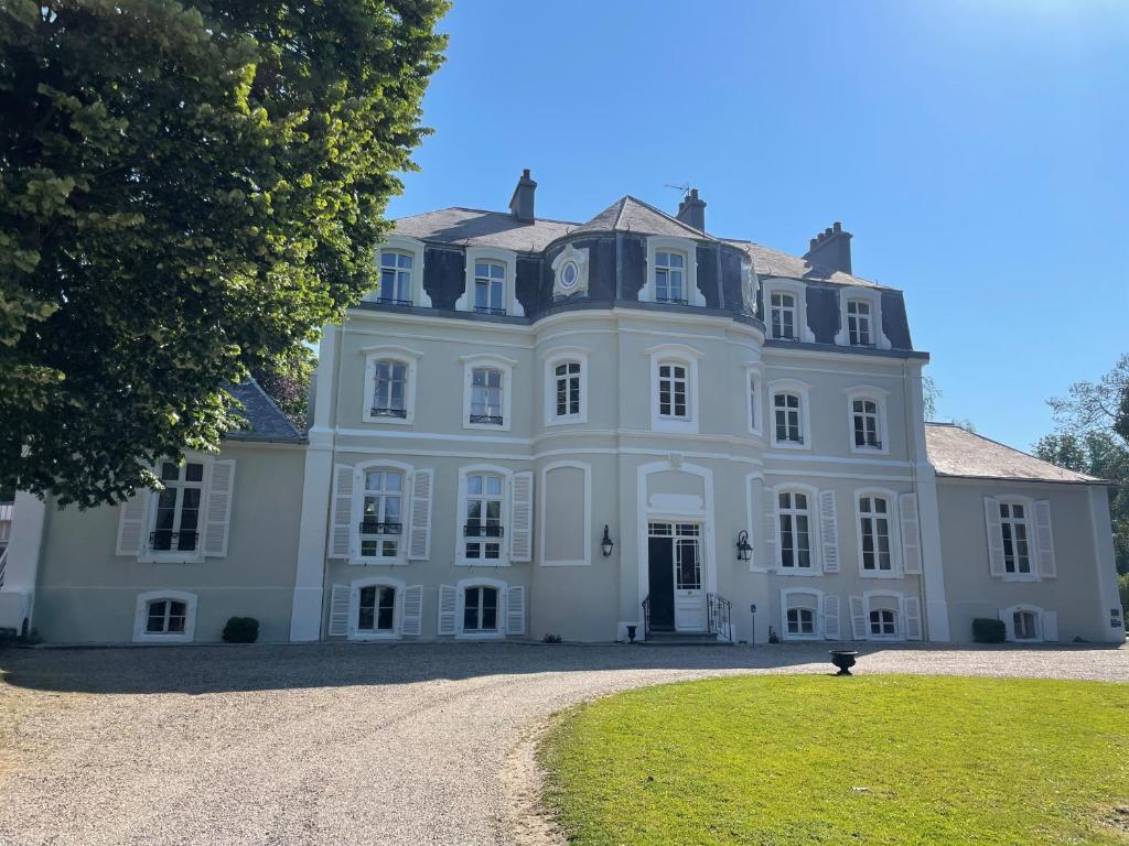 une grande maison blanche avec un arbre en face dans l'établissement Hôtel Château Cléry, à Hesdin-lʼAbbé