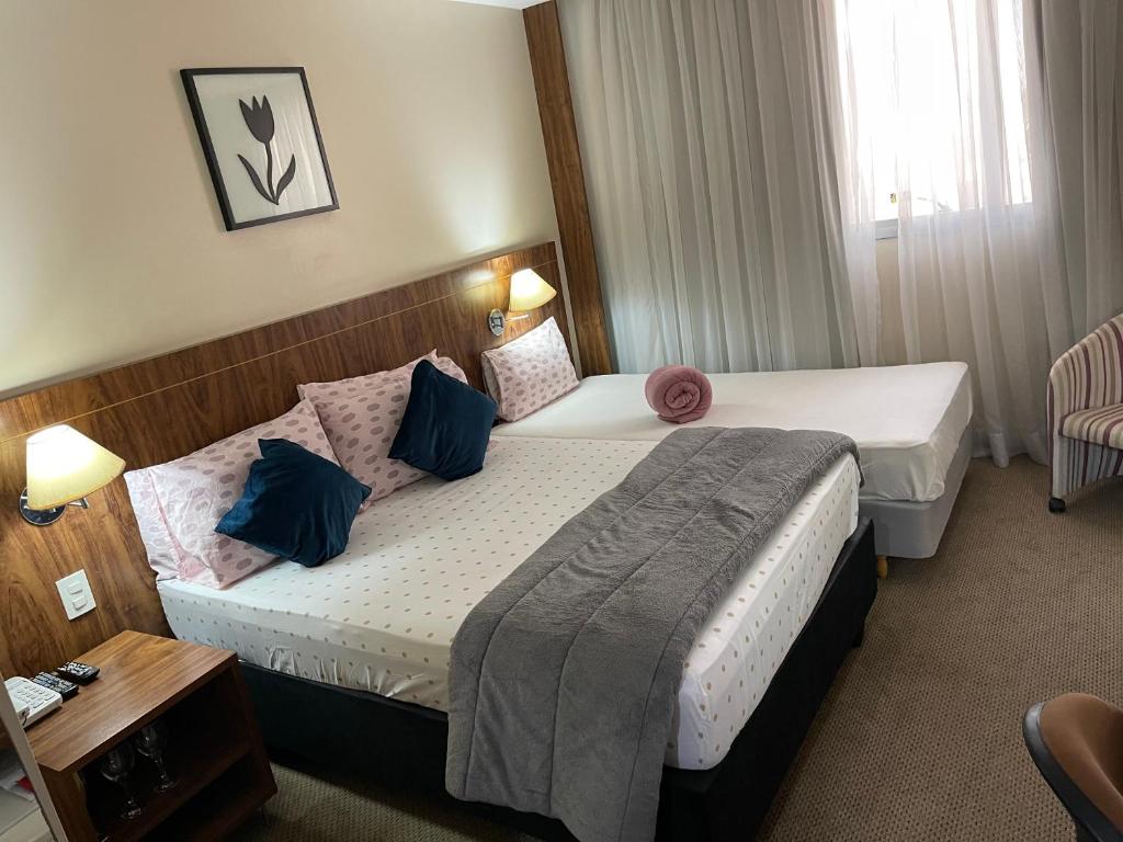 a hotel room with two beds and a table at PROMOÇÃO EXECUTIVA COM BANHEIRA E FLATS SEM BANHEIRA- Melhor Hotel De Taguatinga in Taguatinga