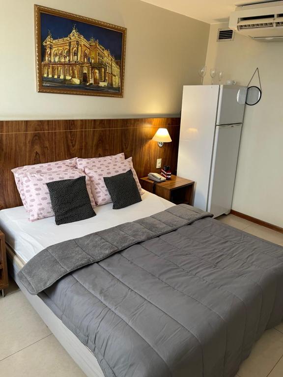 a bedroom with a large bed and a refrigerator at PROMOÇÃO EXECUTIVA COM BANHEIRA E FLATS SEM BANHEIRA- Melhor Hotel De Taguatinga in Taguatinga