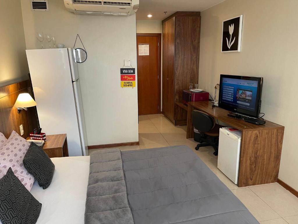 a bedroom with a bed and a desk with a television at PROMOÇÃO EXECUTIVA COM BANHEIRA E FLATS SEM BANHEIRA- Melhor Hotel De Taguatinga in Taguatinga