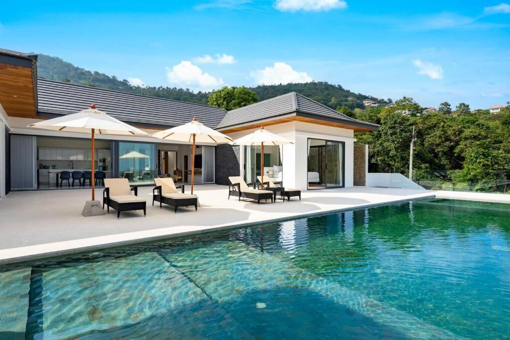 una piscina con sillas y sombrillas junto a una casa en Villa Mandra - Beautiful 4 Bedroom Luxury Pool Villa KBR2 en Koh Samui