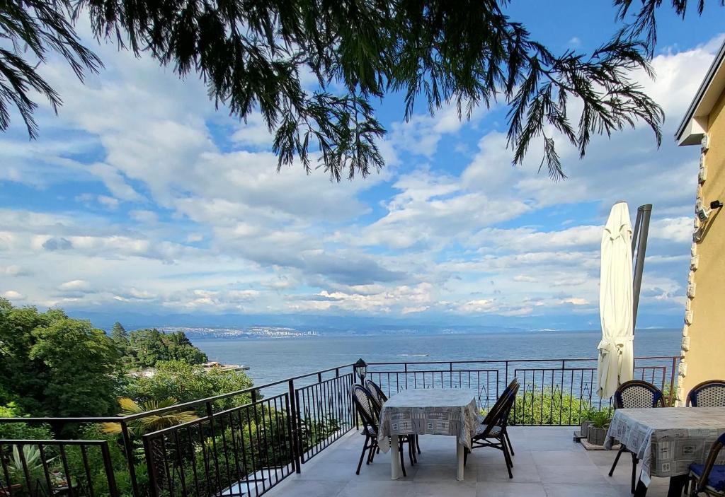 een balkon met tafels en stoelen en uitzicht op de oceaan bij House Vali in Lovran