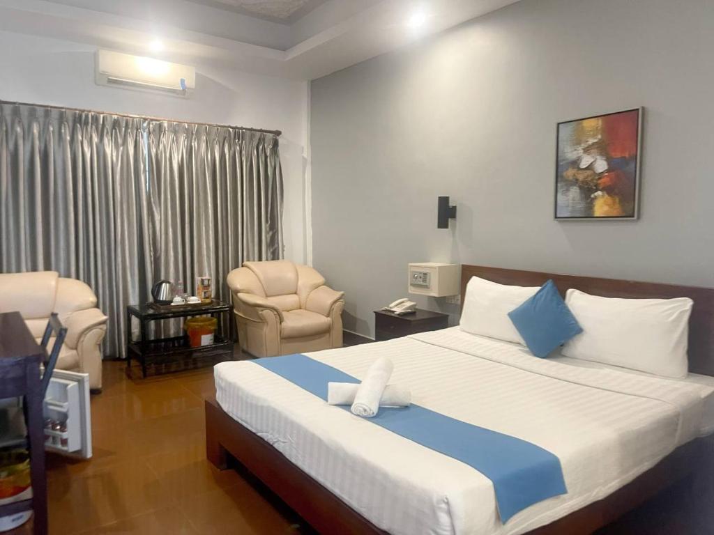 Pokój hotelowy z łóżkiem i krzesłem w obiekcie Best Central Point Hotel w mieście Phnom Penh